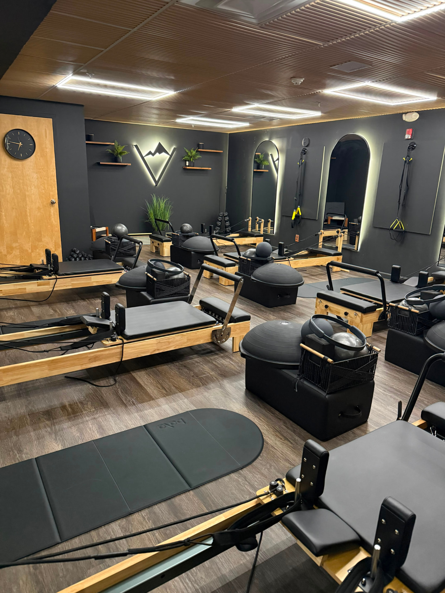 The Valley Studio reformer room with reformers, BOSU balls, TRX straps and the mountain logo on the wall